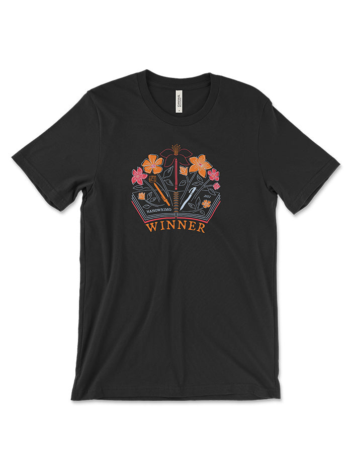 Black t-shirt for 2022 NaNoWriMo winners. In the center of the shirt there is a bright orange, pink and white graphic of flowers and pencils growing out of an open book. Text reads NaNoWriMo 2022 Winner.