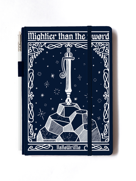 Dark blue journal with white pencil attached at the side. The journal’s cover features awhite illustration of a pen plunged into a large rock. The background include small stars and a curly border. Text reads “Mightier than the sword” and “NaNoWriMo.”